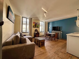 Una sala de estar con un sofá, una mesa de comedor con sillas, un televisor y una chimenea.
