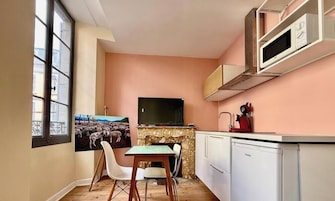 Una cocina compacta con zona de comedor, televisor y microondas.