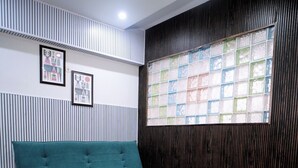A modern living room with a teal sofa, a glass coffee table, and a patterned rug. - The Bless Code (Lucknow)