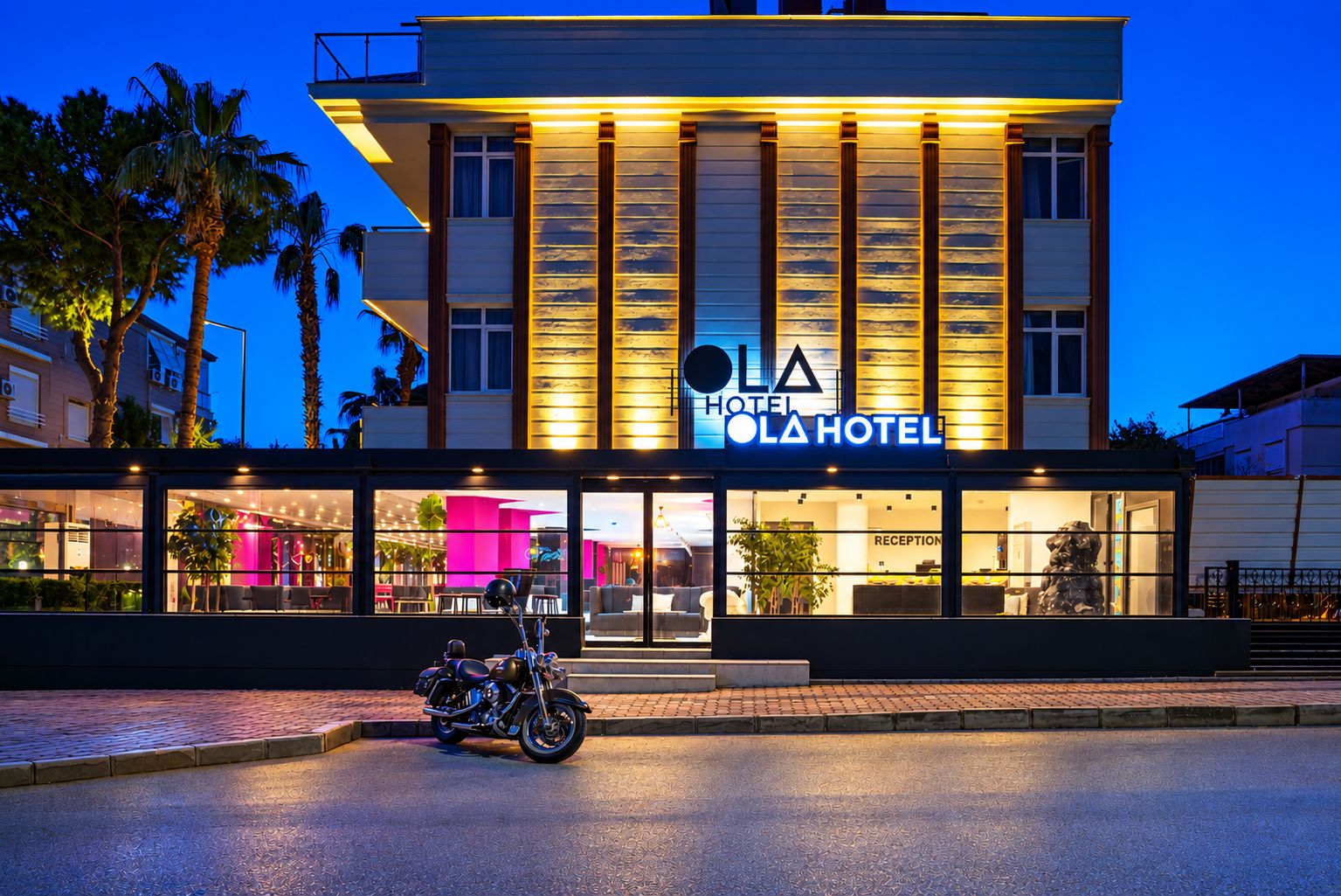A modern hotel with a prominent sign, a reception area, and a motorcycle parked in front.