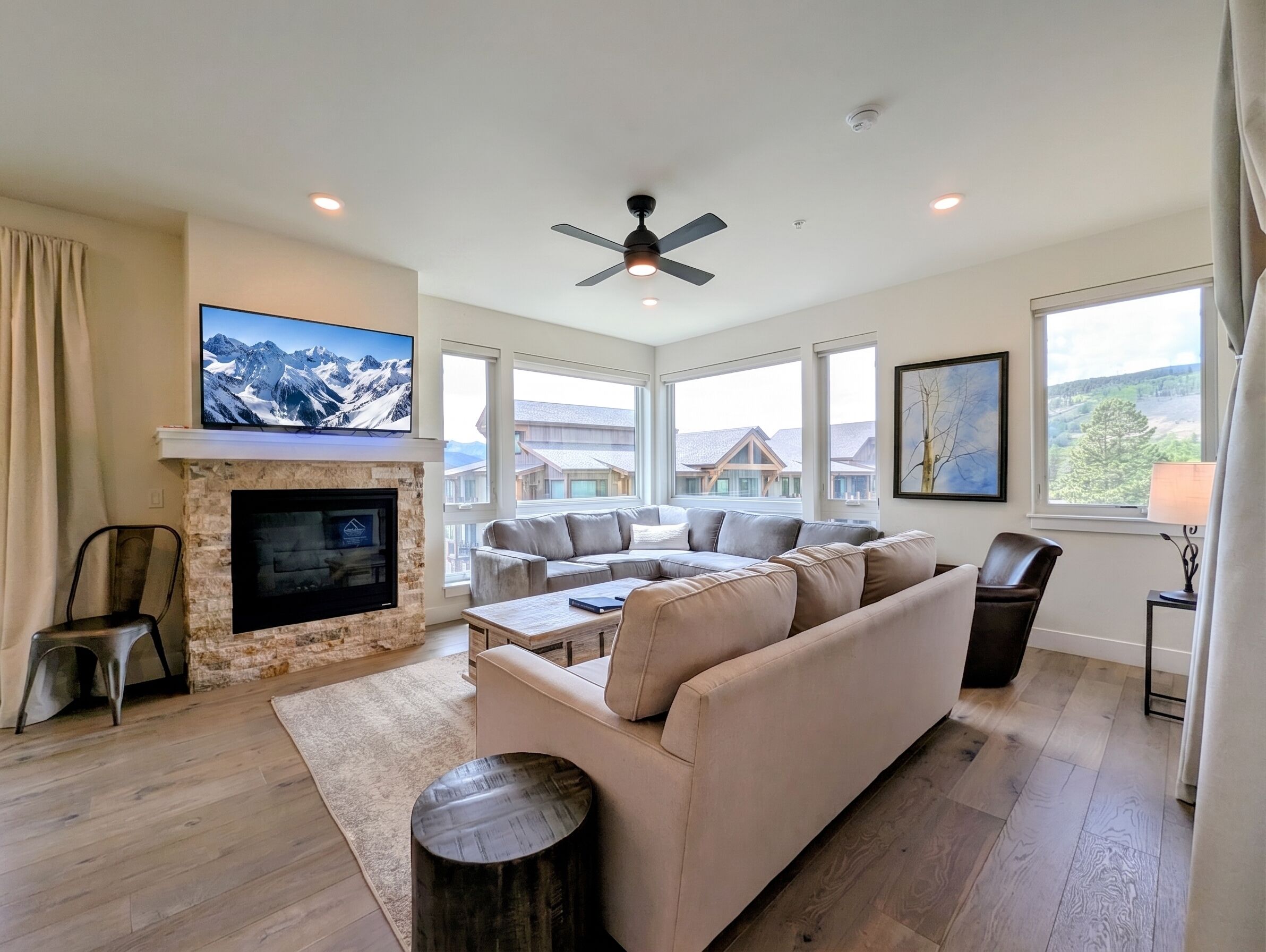 A spacious living room with a fireplace, a large sectional sofa, and a flat-screen TV mounted on the wall.