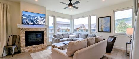 A spacious living room with a fireplace, a large sectional sofa, and a flat-screen TV mounted on the wall.