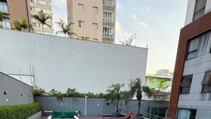 Une piscine rectangulaire avec une terrasse en bois, entourée de chaises longues et d’un petit jacuzzi.