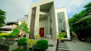 A modern house with a central tower, a covered patio with chairs, and a well-maintained garden. - Stadler Resort (Wadduwa)
