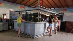 Angolo bar con bancone, bicchieri e bottiglie.