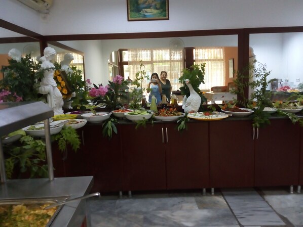 A buffet setup with various dishes, a decorative white sculpture, and potted plants. - Bariscan Hotel – All Inclusive (Alanya)