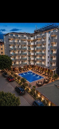 A multi-story hotel with a rooftop pool, outdoor seating, and a parking area.. Bariscan Hotel – All Inclusive