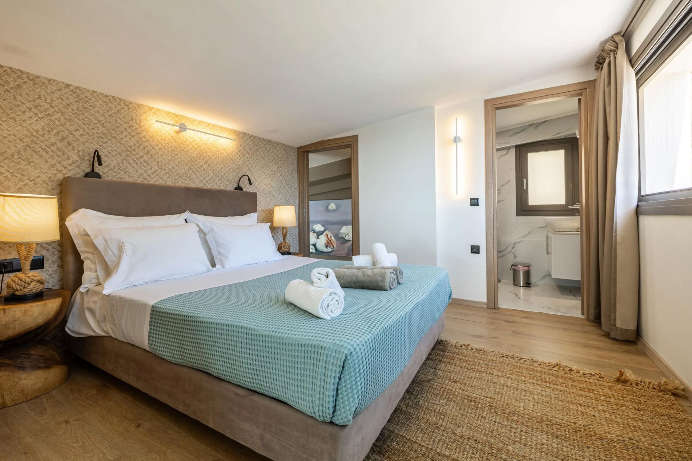 A neatly made bed with a green checkered bedspread, two bedside lamps, and a wooden nightstand with a lamp and a decorative item.