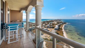 Ein Balkon mit Blick auf Meer und Strand, ein Essbereich mit Tisch und Stühlen sowie ein klarer Himmel.