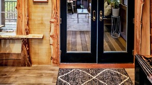 Un interior de madera con un amplio ventanal corredero que da a una terraza exterior.