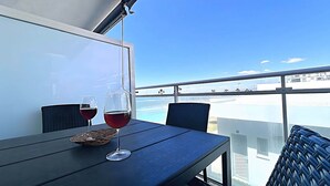 A balcony with a table, two wine glasses, and a basket. - Dunas Beach - Sea View (Torrox)