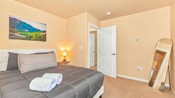 Une chambre à coucher avec un lit, une table de chevet, une lampe, une porte et un miroir.