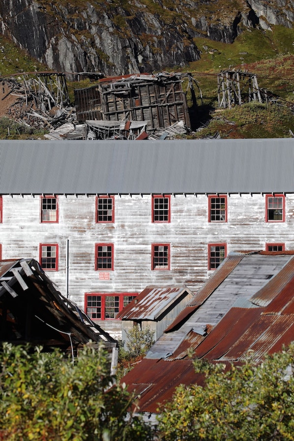A rustic building with multiple windows and a metal roof, surrounded by rocky terrain and greenery. - Cozy Fairbanks Escape with Space to Unwind WIFI (Fairbanks)