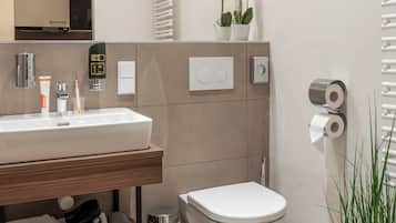 Un baño moderno con lavamanos, inodoro y una planta en maceta.