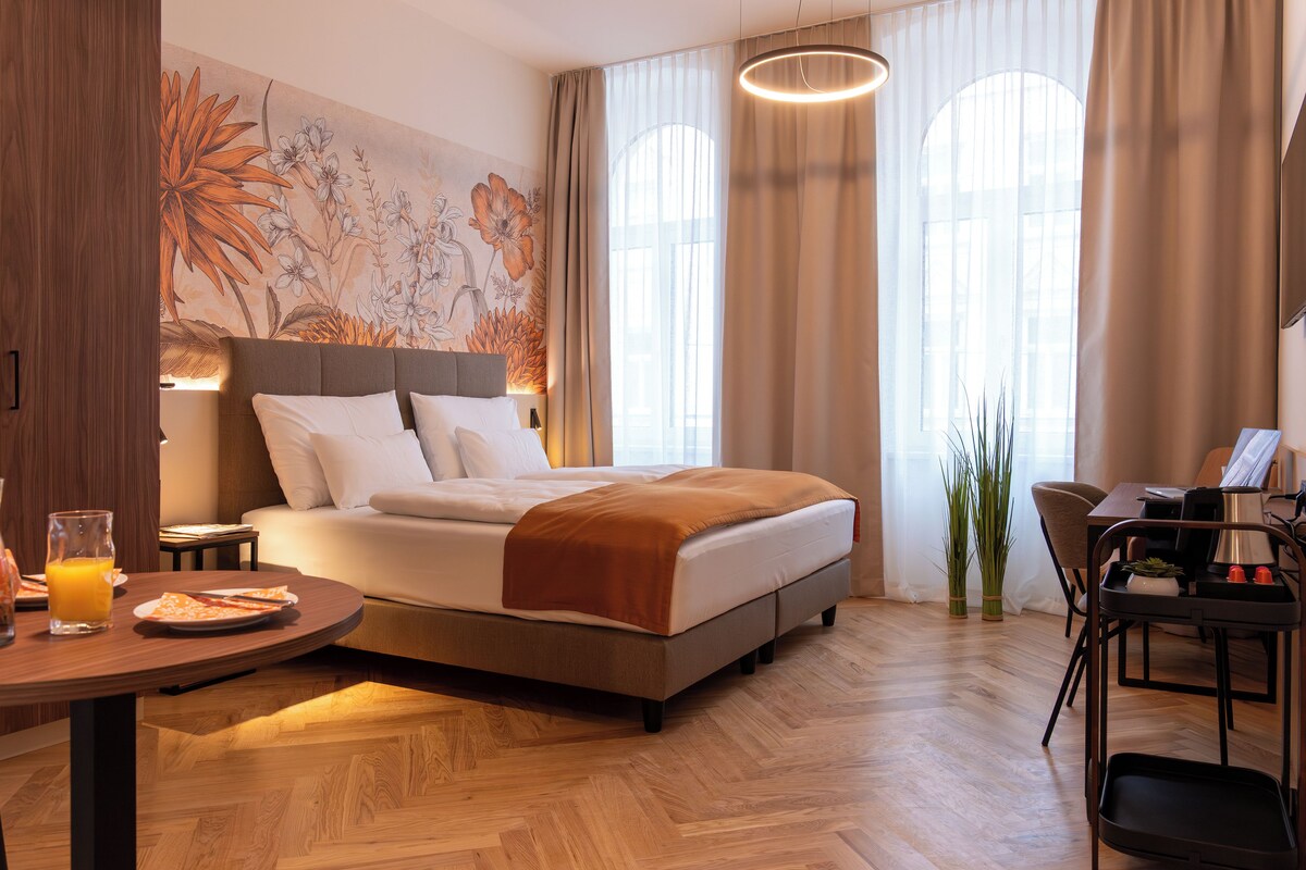 Habitació d'hotel moderna amb un llit gran, una taula de menjador i un escriptori.