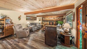 A cozy living room with a fireplace, leather chairs, and a wooden ceiling. - Gatlinburg Cabin with Hot Tub, Game Room, Sleeps 12 (Gatlinburg)