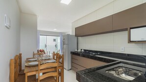 Ett modernt kök med matplats, utrustat med en bänkskiva i granit, en diskho i rostfritt stål och en inbyggd ugn.