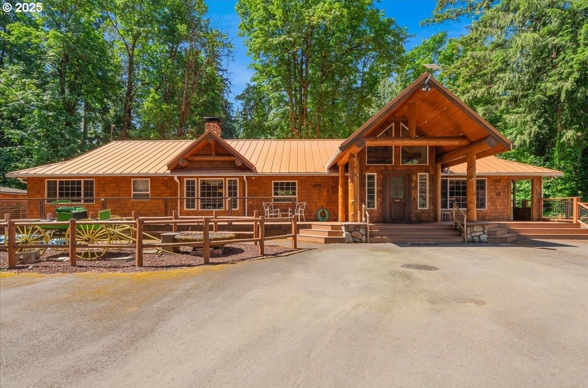 The Main Lodge — the heart of the estate. Timber beams, a wraparound porch, six of the eight bedrooms, and every gathering space inside. All of it is yours.
