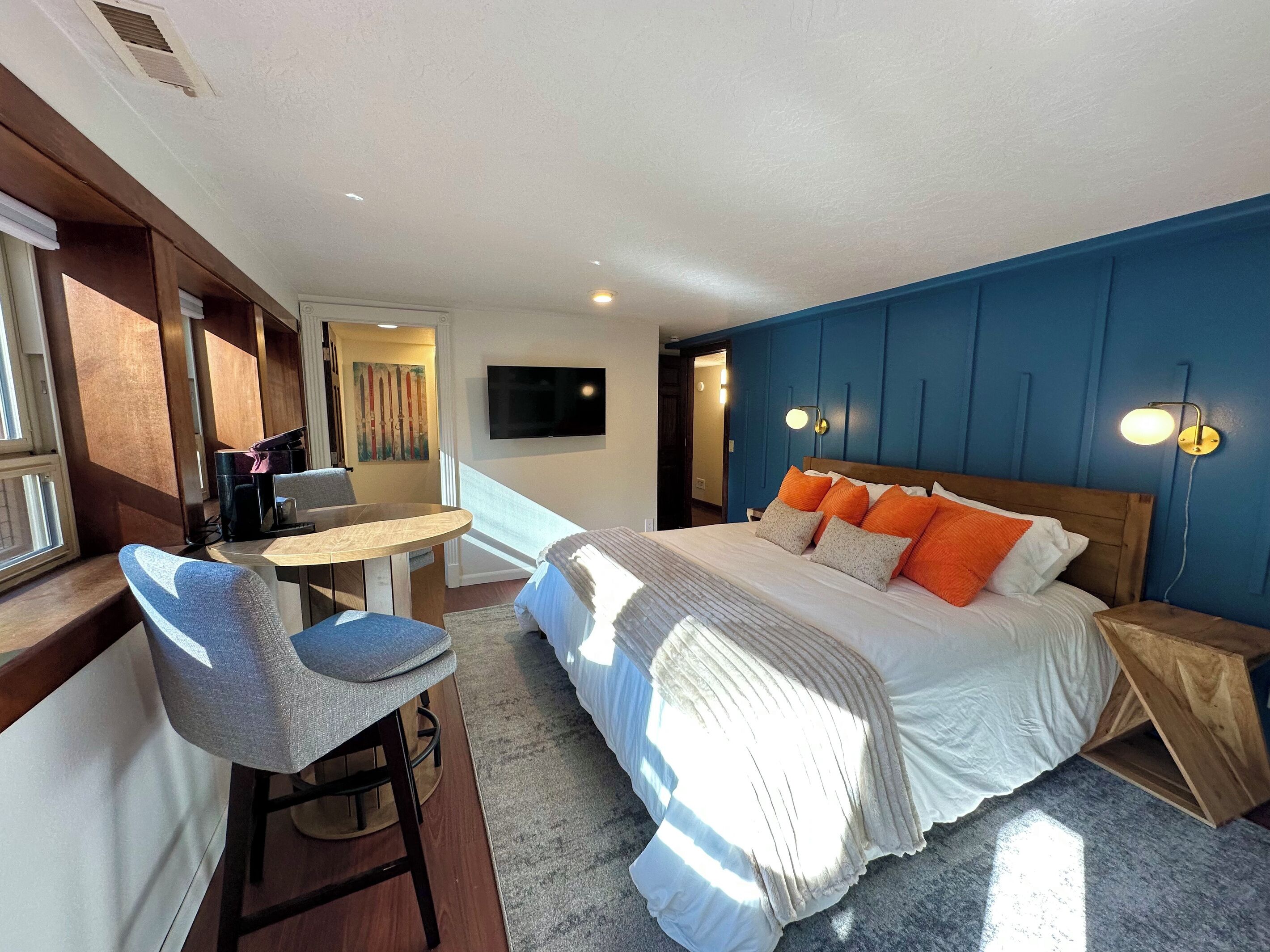 Une chambre d’hôtel avec un lit, un bureau, une chaise, une télévision et une fenêtre.