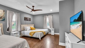 Ein modernes Schlafzimmer mit einem Bett, einem Fernseher und einem Deckenventilator.