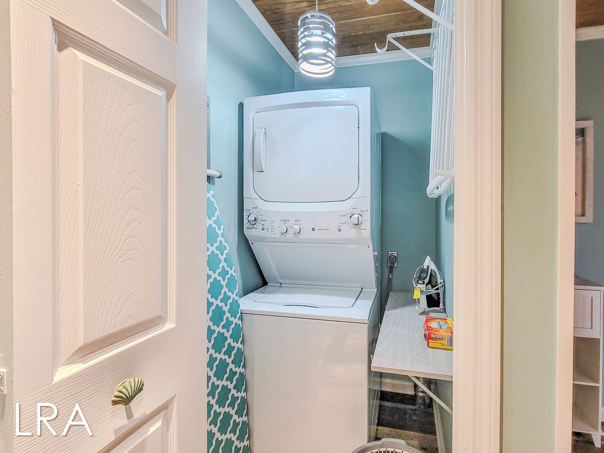 A laundry room with a washing machine, a drying rack, and a towel rack.