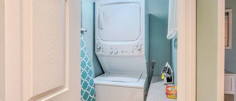 A laundry room with a washing machine, a drying rack, and a towel rack.