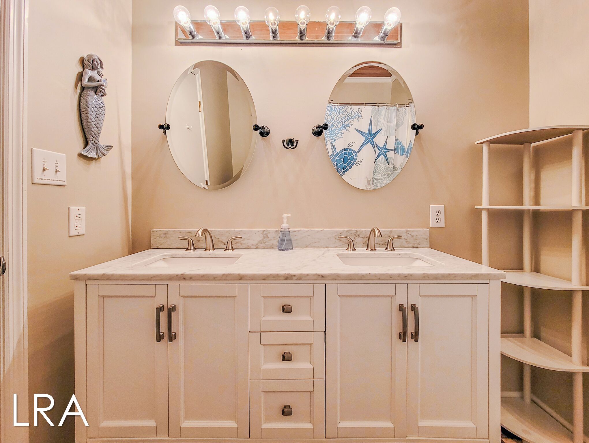 Un baño con dos lavamanos, un espejo grande y un mueble de tocador con cajones.