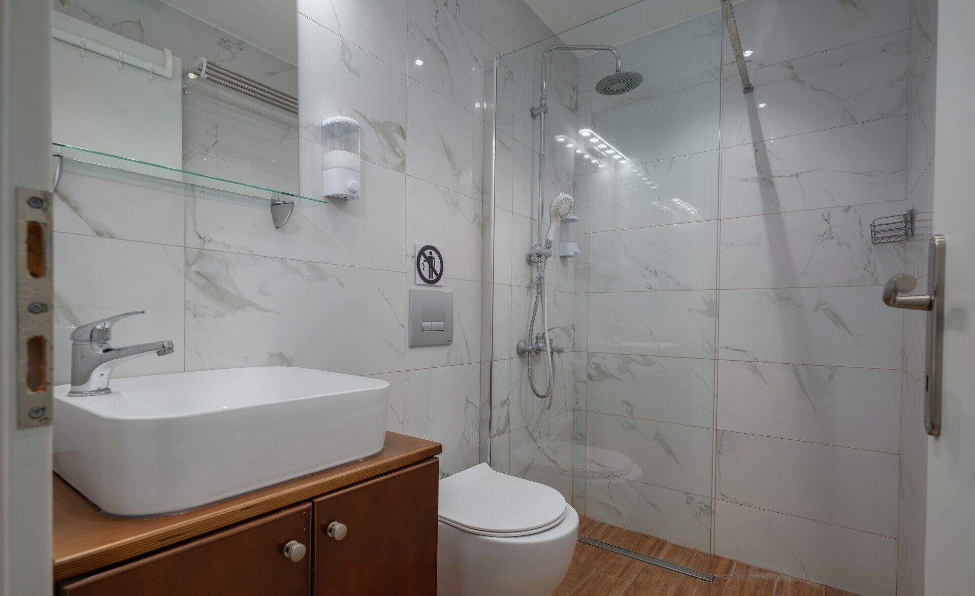 A bathroom with a white sink, a toilet, and a glass-enclosed shower area.