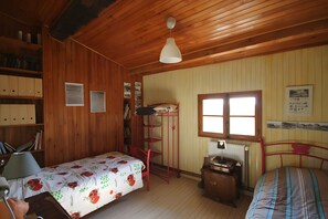 Una habitación con paneles de madera, una cama, un escritorio, una silla y una estantería.