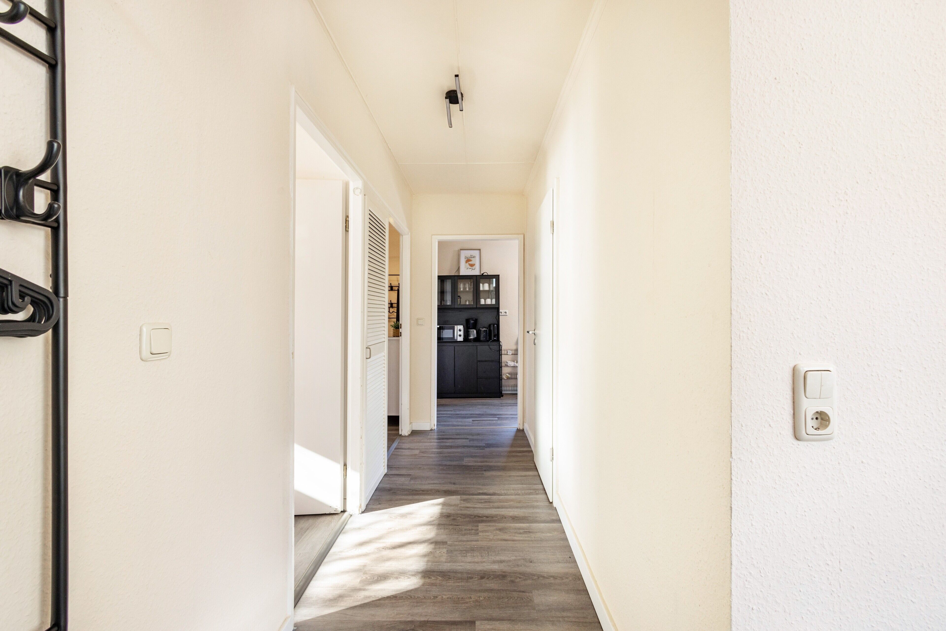 A hallway leading to a kitchen with a microwave and cabinets.