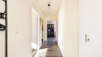 A hallway leading to a kitchen with a microwave and cabinets.