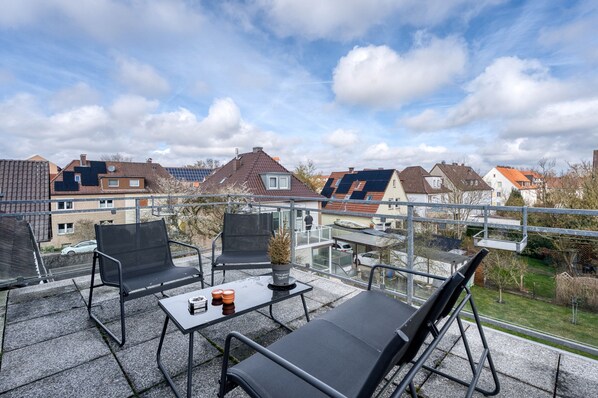 Un balcon avec un espace salon extérieur, une table et un pot de fleurs.