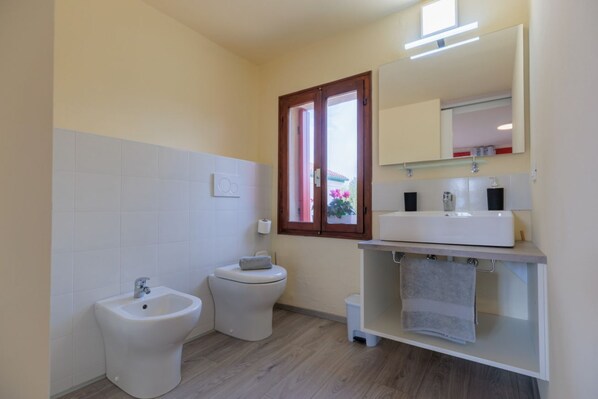 Une salle de bain moderne équipée d’un bidet, de toilettes et d’un meuble-lavabo avec un miroir.