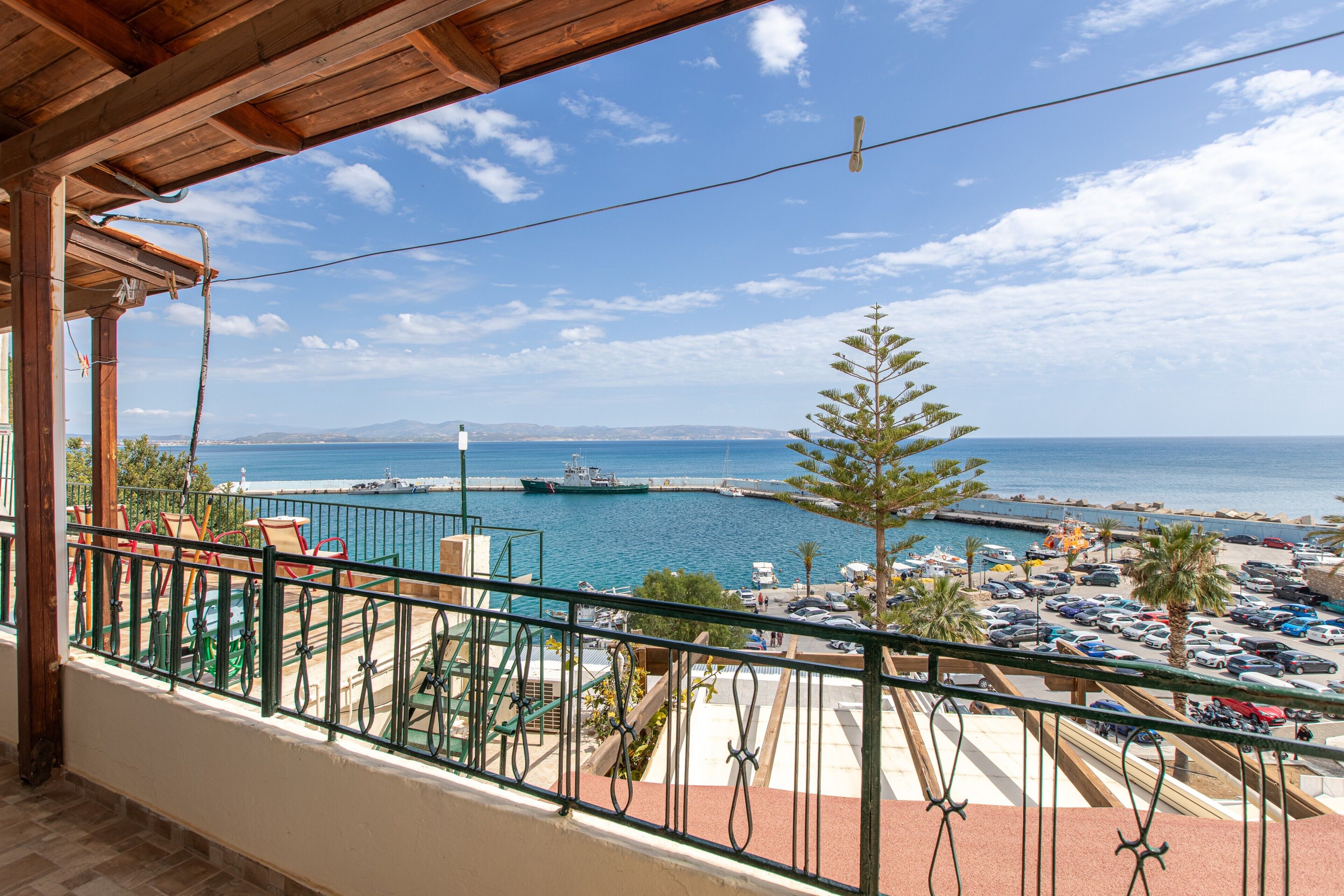 Un balcon avec vue sur une marina, des bateaux et un ciel dégagé.