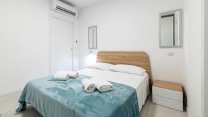 Et rent, moderne soveværelse med seng, sengebord og klimaanlæg.
