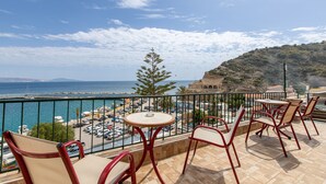 A balcony with a view of the sea, a parking lot, and a building in the background. - Apartment 'Two Bedroom  Sea View' with Sea View, Wi-Fi and Air Conditioning (Crete)