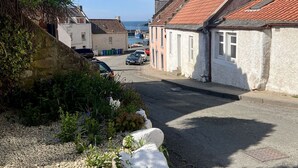 A narrow street with traditional buildings, a clear sky, and a distant view of the sea. - Bayview Townhouse | St Monans (St Monans)