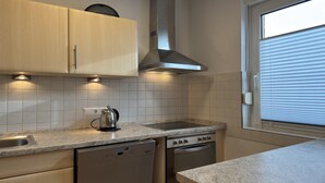 Una cocina equipada con lavavajillas, horno y ventana con persianas.