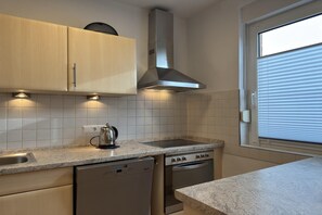 Eine Küche mit Geschirrspüler, Backofen und einem Fenster mit Jalousien.