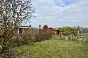 Il s’agit d’une propriété résidentielle dotée d’une cour clôturée, d’une maison à toit rouge et d’un abri de jardin.