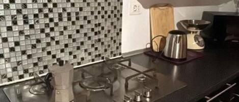 A kitchen with a gas stove, a coffee maker, and a microwave.