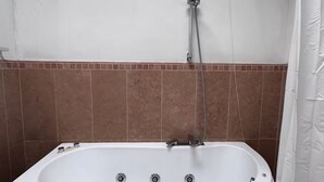 Une salle de bain avec une baignoire, une douche et des murs carrelés.