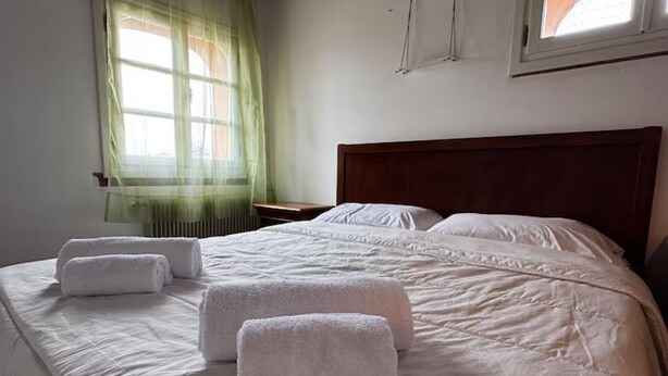 Un lit bien fait, avec des draps blancs et deux serviettes enroulées posées dessus.