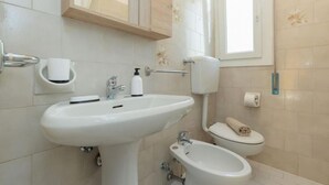Een badkamer met een wastafel, bidet, toilet en spiegel.