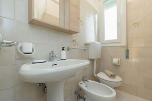 Ein Badezimmer mit Waschbecken, Bidet, Toilette und Spiegel.