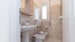 Ein kleines, sauberes Badezimmer mit Waschbecken, Toilette, Bidet und Dusche.