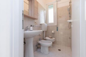 Ein kleines, sauberes Badezimmer mit Waschbecken, Toilette, Bidet und Dusche.