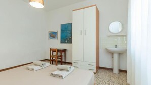 Ein Schlafzimmer mit Bett, Stuhl, Kleiderschrank, Waschbecken und einem Gemälde an der Wand.
