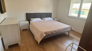 A bedroom with a bed, nightstands, a window, and a door. - The Space🌟 Your Exclusive Retreat in the Heart of Jesolo – Comfort, Style, and an Unbeatable Location 🌟Imagine waking up with the scent of the sea in the air, having breakfast on a private terrace overlooking Jesolo’s famous walking street, and (Lido di Jesolo)