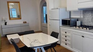 A modern kitchen with white cabinets, a marble countertop, a gas stove, and a microwave. - The Space🌟 Your Exclusive Retreat in the Heart of Jesolo – Comfort, Style, and an Unbeatable Location 🌟Imagine waking up with the scent of the sea in the air, having breakfast on a private terrace overlooking Jesolo’s famous walking street, and (Lido di Jesolo)